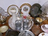 Overview of assorted porcelain, metalware, and glass items on tabletop