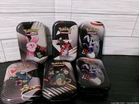 Six metal Pokémon tins standing upright