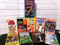 Group shot of ten boxed sports bloopers VHS tapes in front of backdrop