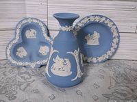 Front view of blue jasperware bud vase, round dish and trefoil dish showing white relief decoration