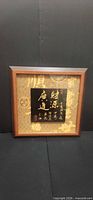 Front view of framed calligraphy art showing frame, background, plaque and gold characters