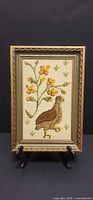 Front view of framed needlepoint showing bird and flowers