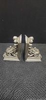 Side view of both metal bookends showing ornate scroll design