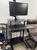 Front view of black standing desk with monitor arm, keyboard shelf visible