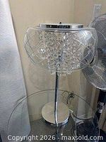 Full view of chrome table lamp with crystal shade on glass table