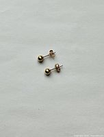 pair of gold stud earrings on neutral background