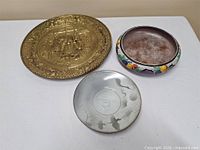 All three items: brass plaque, fruit motif bowl, grey bowl