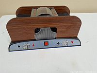 Front and side view of the plastic automatic card shuffler showing faux wood grain sides and control panel