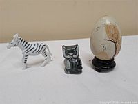 overview of zebra, stone owl, painted egg on stand