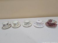 Five tea cup and saucer sets lined up