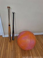 Exercise ball and two bats leaning against wall