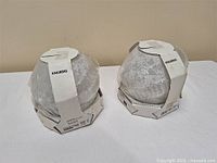 Two packaged IKEA KNUBBIG globe fixtures side by side