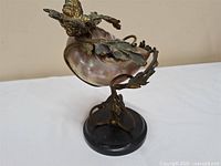 Full view of sculpture showing shell, metal foliage, bird and marble base