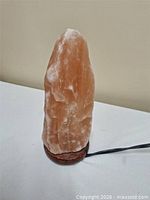 Front view of pink Himalayan salt lamp on wooden base