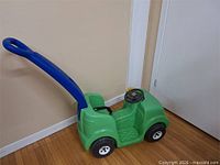 side view of green ride-on car showing blue handle and wheels