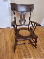 Full view of rocking chair showing carved back, spindles, rockers