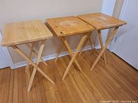 Three light wood folding tables standing side-by-side
