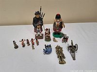 Group view of wooden figures, toy soldiers, brass door knocker, bagpipe model and metal cannon