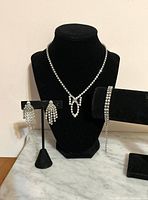 Necklace on bust, bracelet on roll, earrings on stand