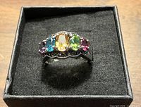 Angled view of sterling silver ring showing five colored gemstones in setting