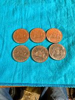 Six 1969 Canadian dollar coins laid out on blue cloth, obverse side showing Voyageur design