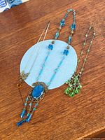 All three necklaces laid out on wooden surface showing overall design and colours