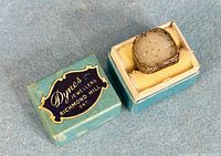 Top view of carved white jade silver filigree ring in open Dynes Jewellers box with lid beside