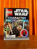 Front cover of the LEGO Star Wars Character Encyclopedia book showing title, graphics, and sealed Han Solo minifigure blister