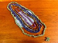 All five gemstone chip necklaces laid out on table