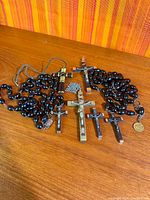 Overall view of rosaries, crucifixes, medal and chain on wood surface
