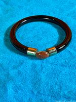 Full view of black glass bangle on blue cloth