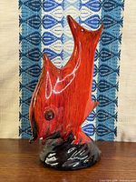 Front view of orange and black drip glaze ceramic angel fish figurine on dark base