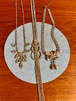 Three rhinestone necklaces on wood surface, details of pendants visible