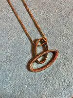 Necklace pendant close-up on gray background showing crystal-set oval and polished oval