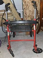 Front view of red 4-wheel rollator walker showing frame, wheels, basket and backrest