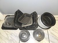 Stack of black meal-prep containers, round white/black bowls and lids