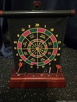 Front view of dartboard on wood base with six darts in holder