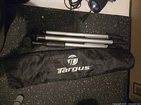 Collapsed Targus tripod beside carry bag and light component