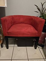 Front view of one red barrel accent chair, showing upholstery and legs