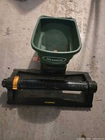 Top view of Scotts spreader and Melnor sprinkler showing overall form and wear