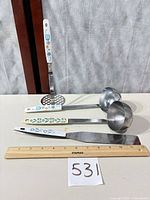 All four utensils beside ruler for scale