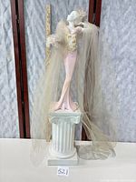 Full view of figurine on pedestal beside measuring stick