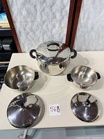 Full set laid out: stockpot with strainer lid, two small pans, two lids