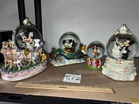 All four Disney snow globes lined up with ruler for scale