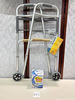 Front view of folded Guardian walker with tags and boxed Omron HEM-7120 monitor placed below