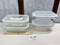 Four stacked glass containers with snap-lock lids; ruler and lot number for scale