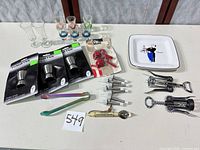 All items laid out including jiggers, pour spouts, corkscrews, opener, tongs, glasses and dish