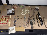 Overview of entire lot on table showing necklaces, bracelets, bangles, earrings, charms and watches