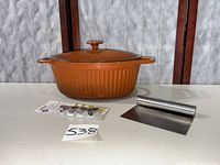 Dutch oven with lid, piping tip set, and bench scraper displayed on table