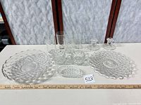 All 11 pressed glass pieces arranged with ruler for scale